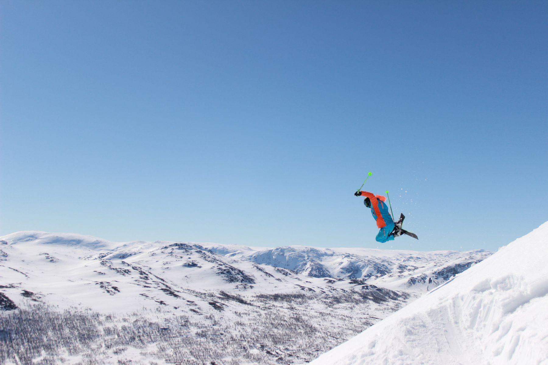 Skier mid-air above a Norwegian mountain plateau